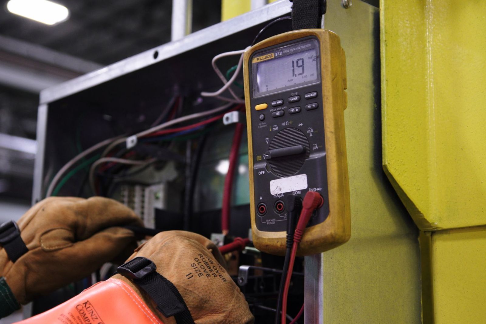 A multimeter being used to test an electrical panel