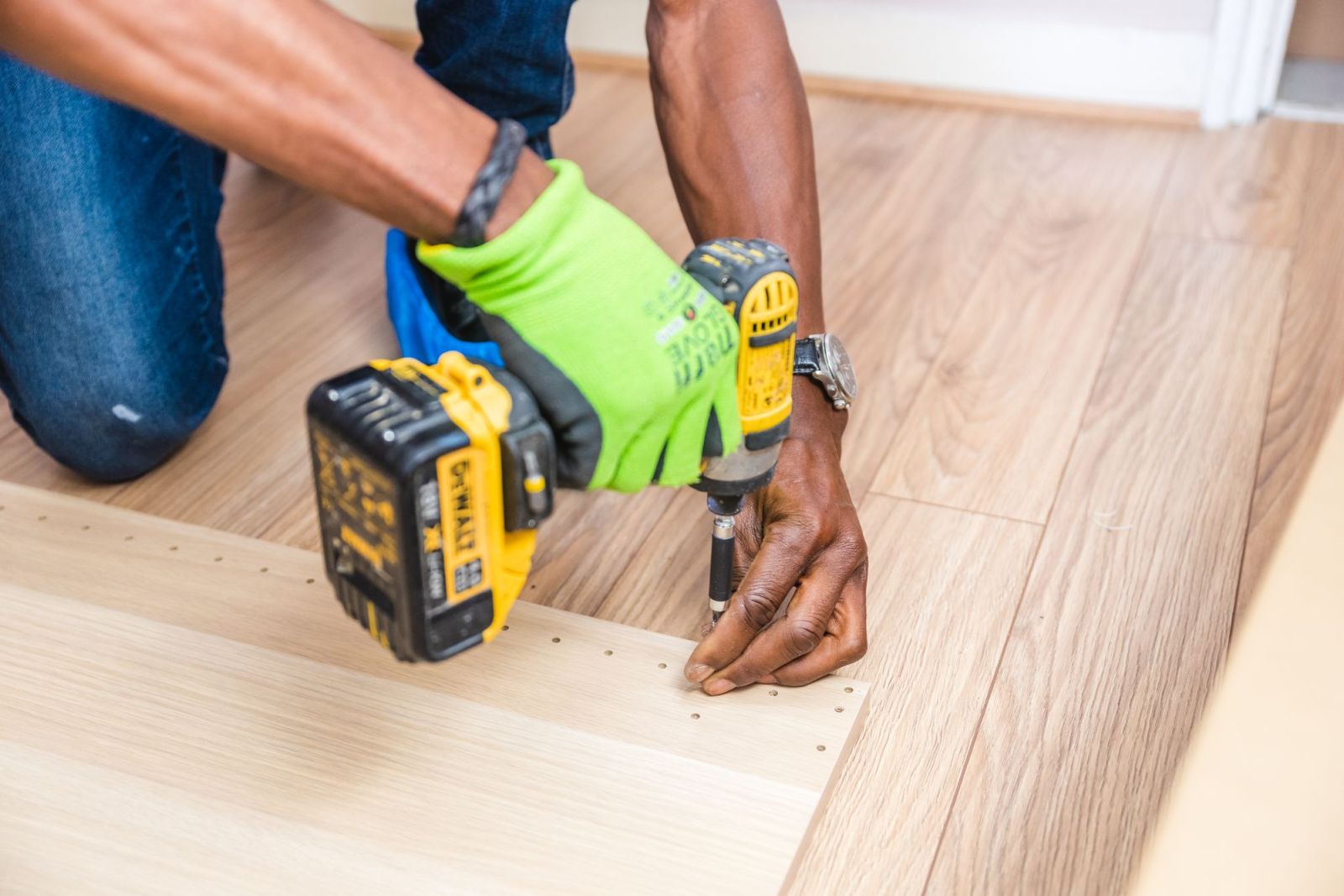 A handyman fixing a floorboard with a cordless drill