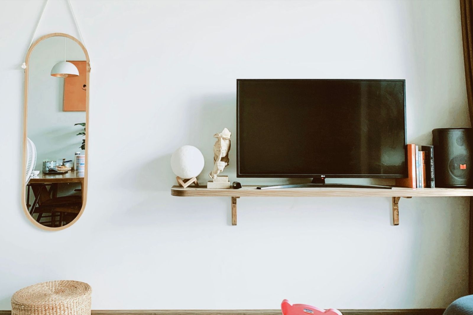 A television, shelf and mirror mounted neatly on a living room wall