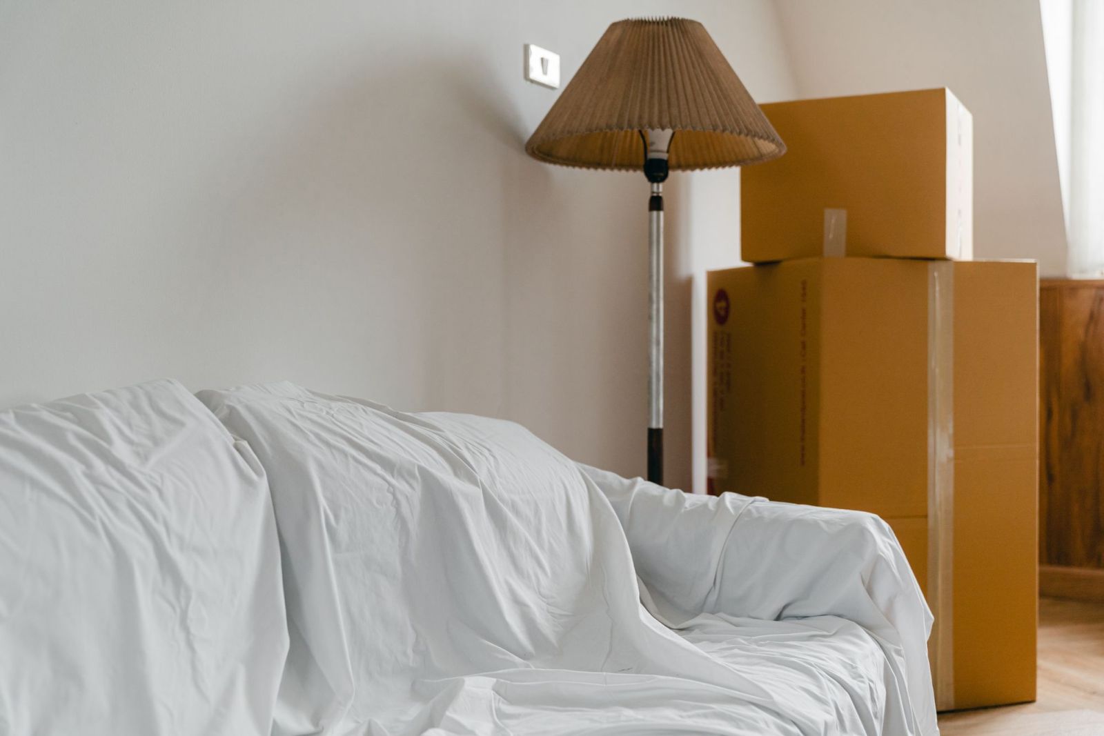 A sofa under a dust sheet beside packed moving boxes