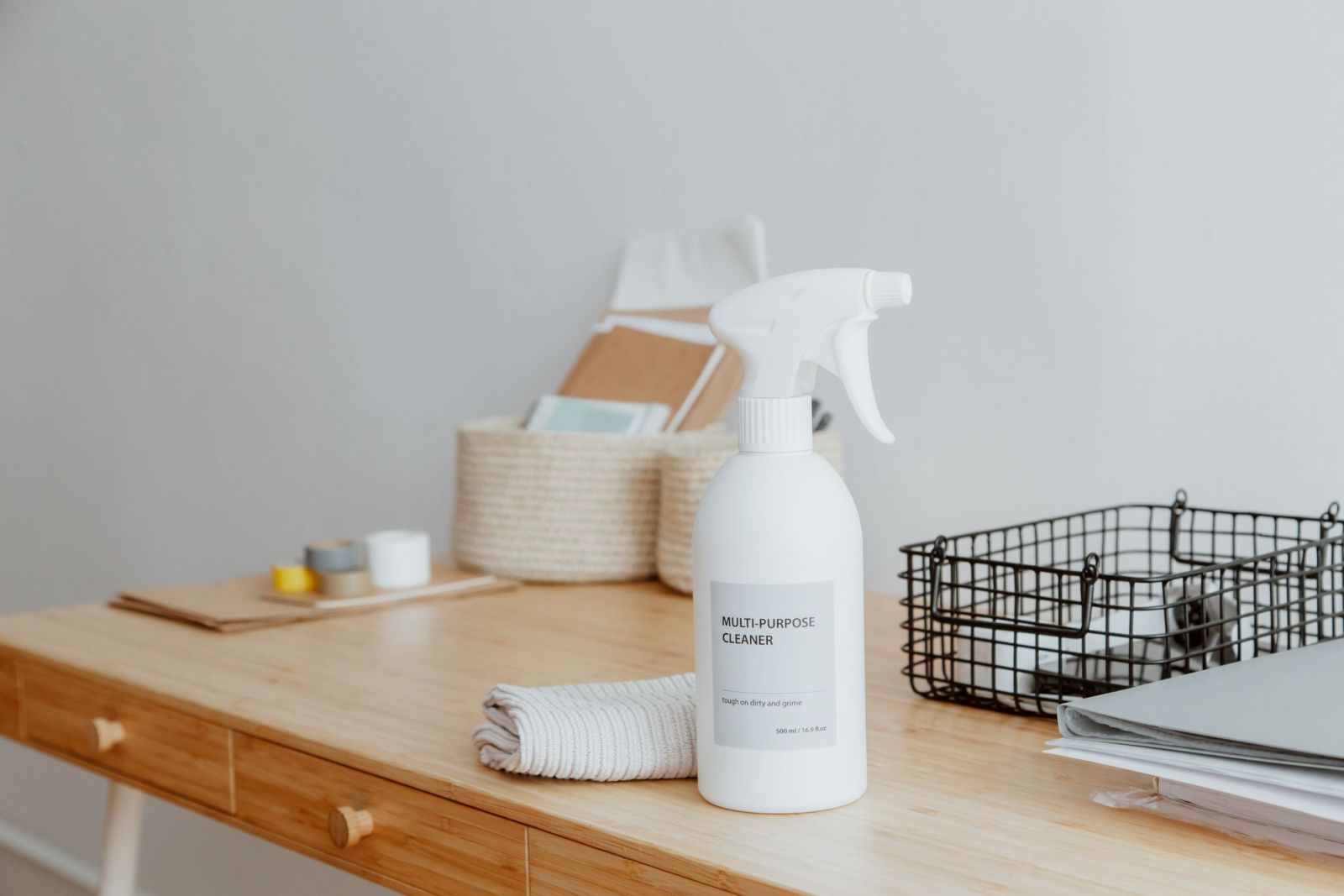 A tidy desk with a spray bottle and cloth ready for cleaning