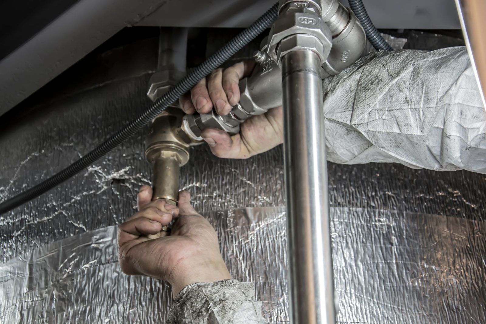A plumber tightening a pipe fitting by hand